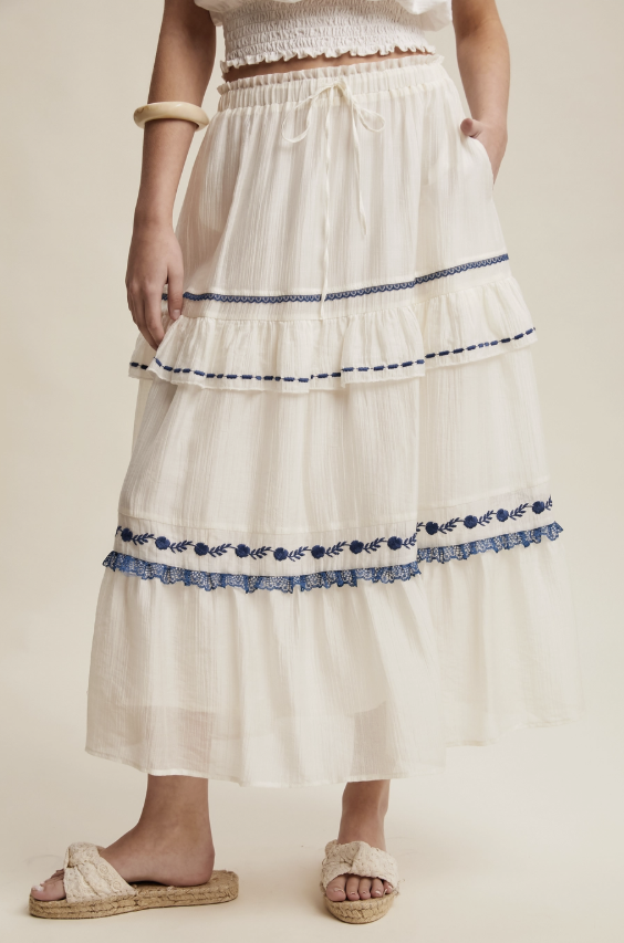 White skirt with blue embroidery on a neutral background