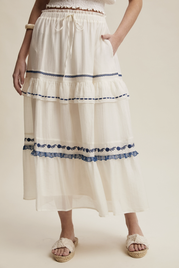 White skirt with blue trim and floral details on a beige background