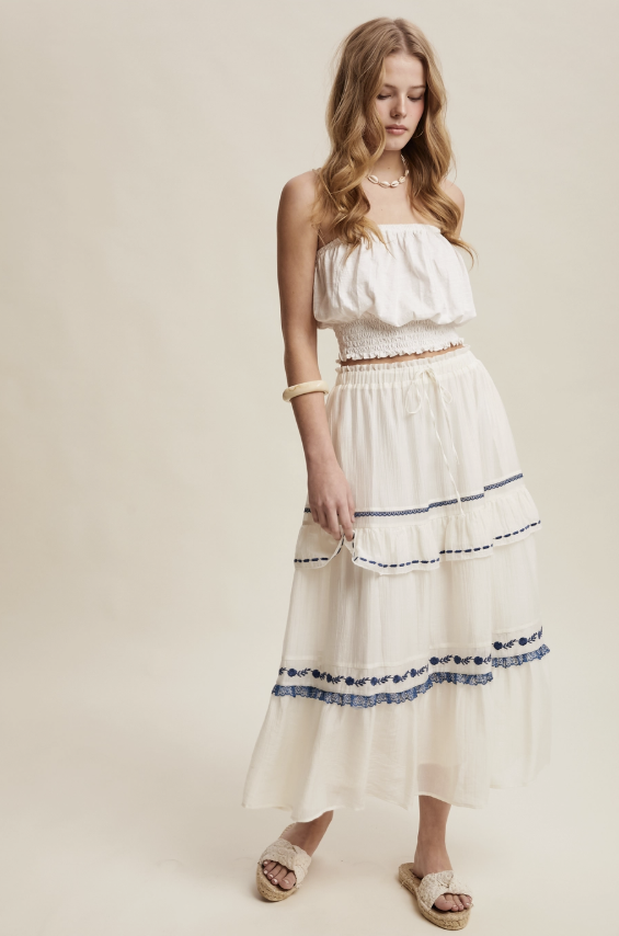 Woman wearing a white dress with blue accents on a beige background