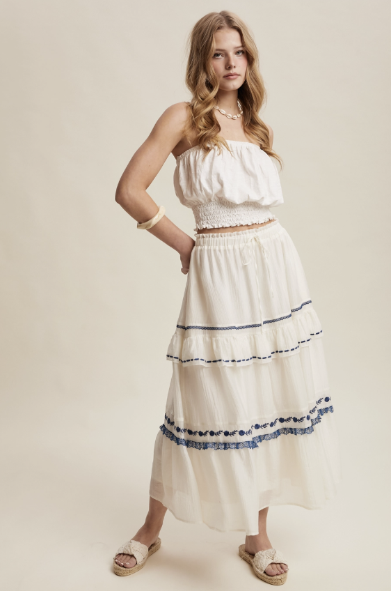 Woman wearing a white dress with blue trim on a beige background