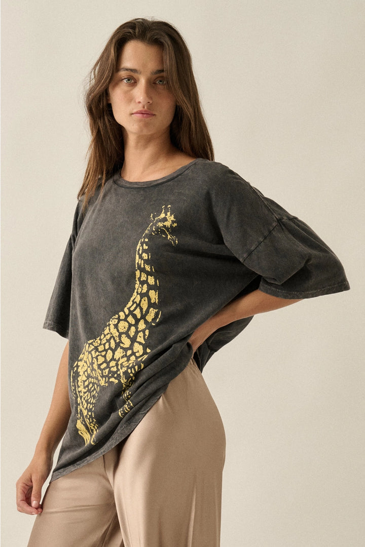 Woman wearing a dark gray t-shirt with a gold giraffe design on a beige background