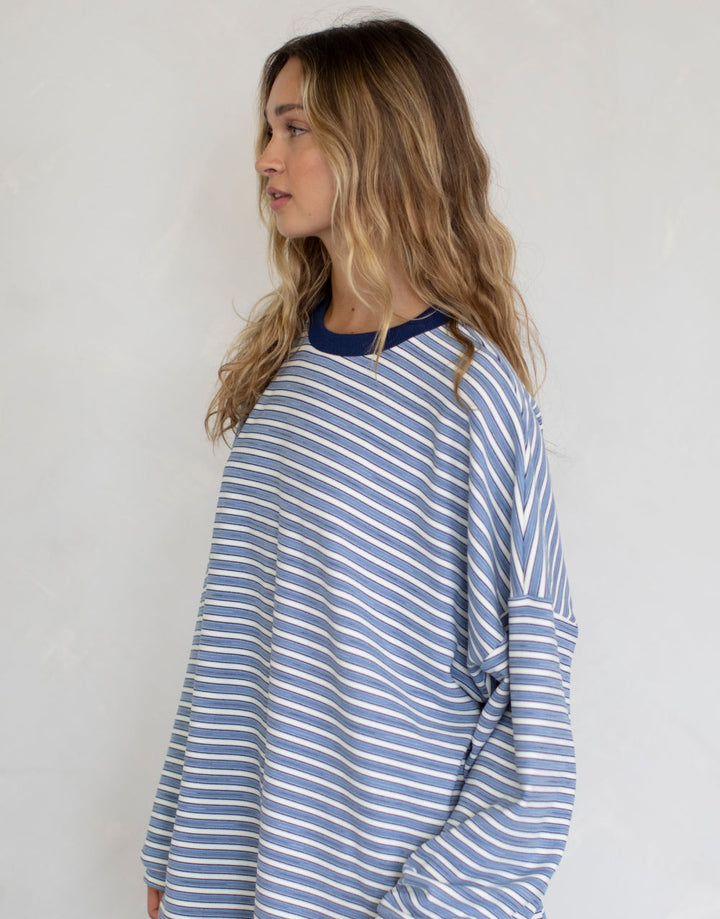 Woman wearing blue and white stipe top on plain background