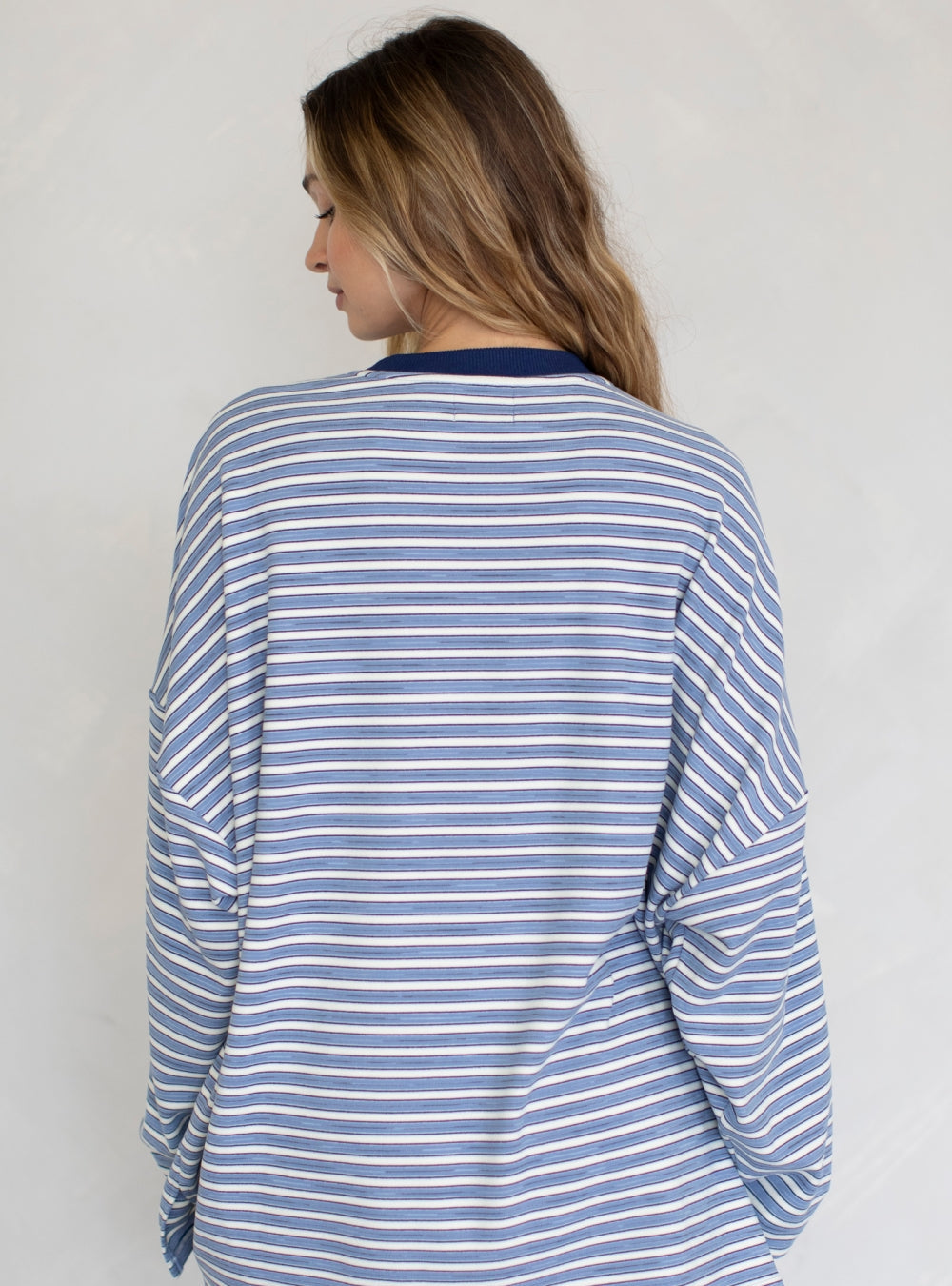 Woman wearing a blue and white striped long-sleeve top against a plain background