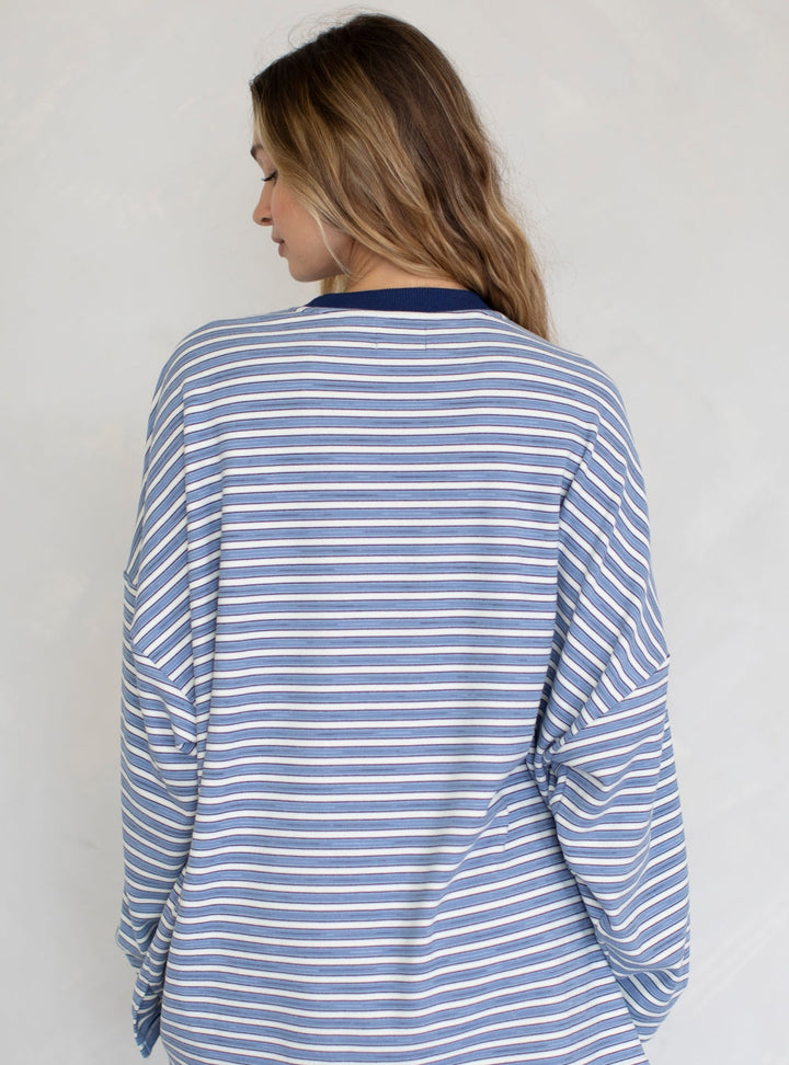 Woman wearing a blue and white striped long-sleeve top against a plain background