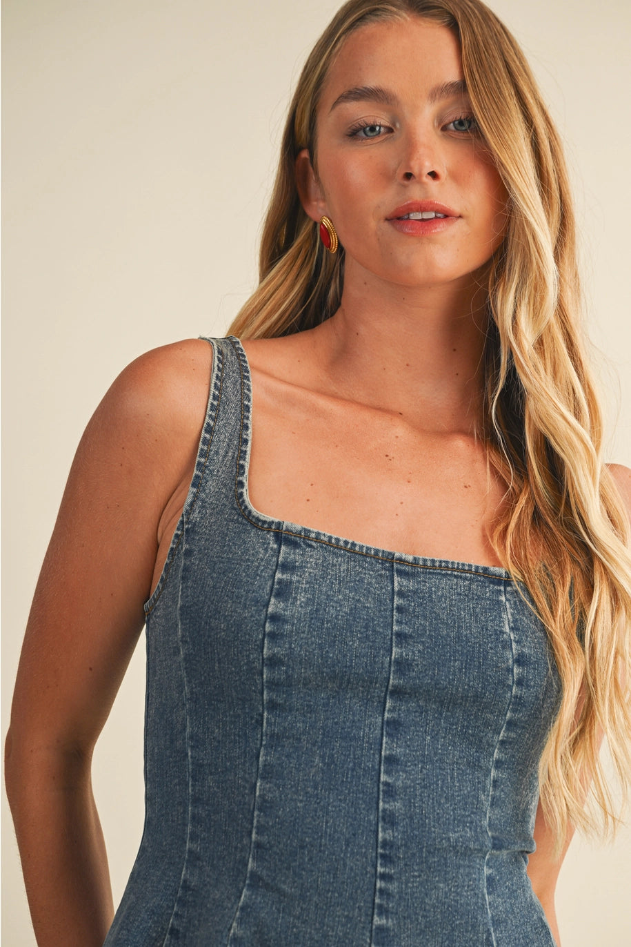 Woman wearing a denim dress against a plain background