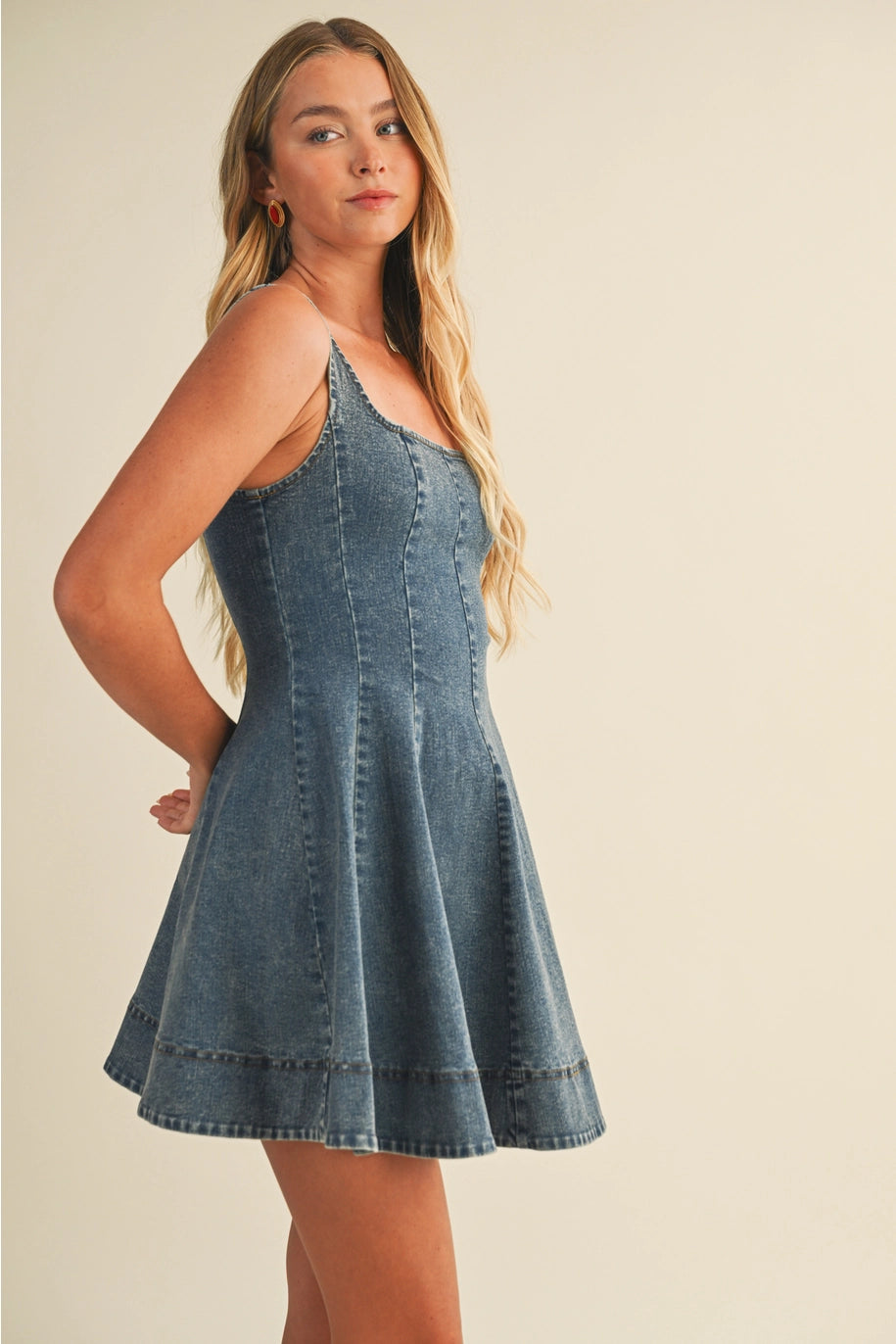 Woman wearing a denim dress against a beige background