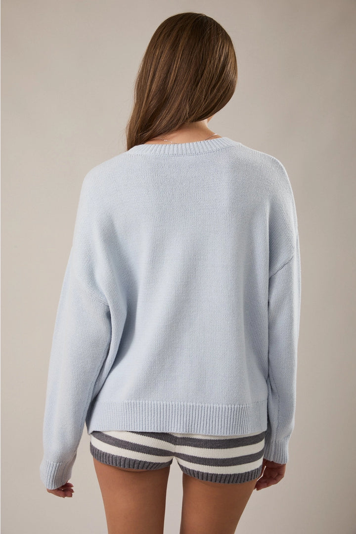 Back of woman wearing light blue sweater on plain background