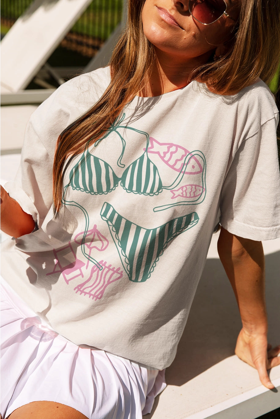 Woman wearing tee with bikini graphics sitting outdoors