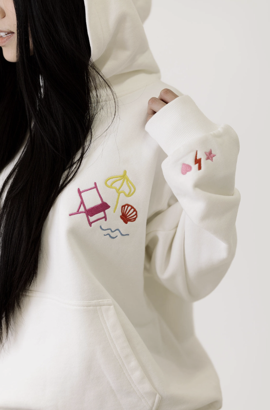 White hoodie with colorful embroidered designs on a plain background