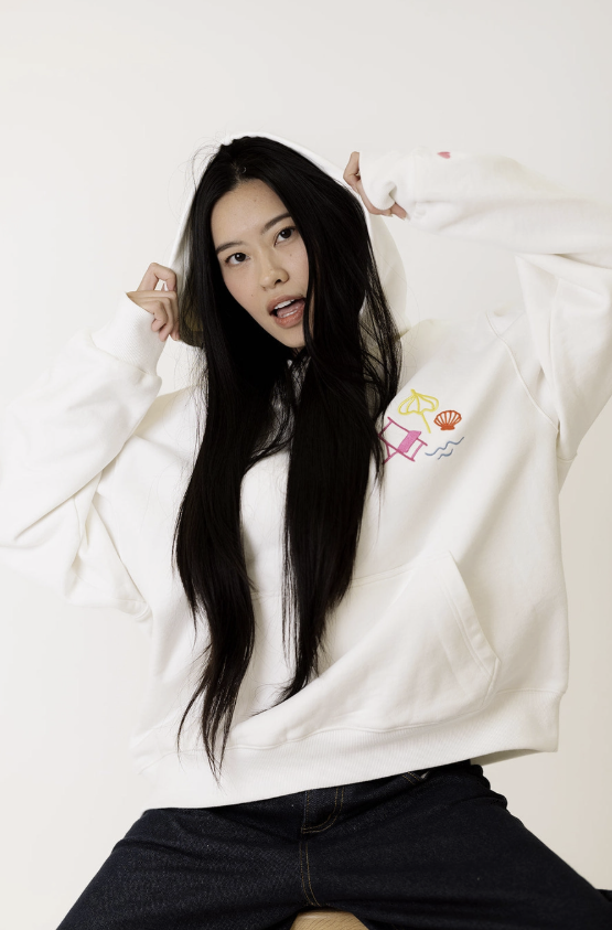Person wearing a white sweatshirt with a cartoon design on a plain background