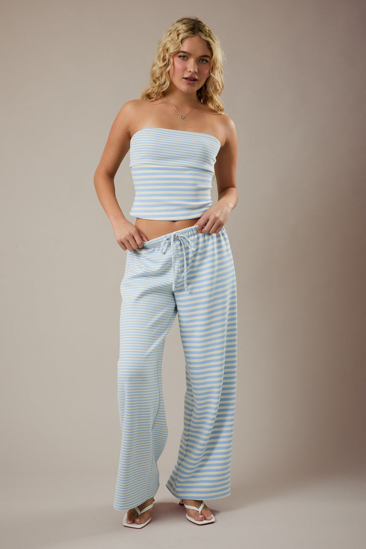 Woman wearing a light blue striped outfit against a beige background