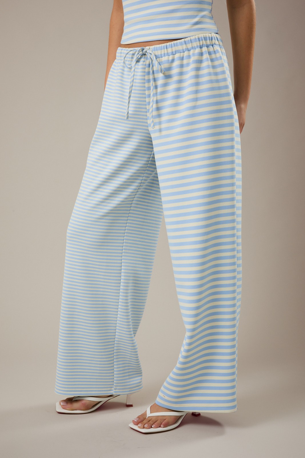 Person wearing light blue and white striped pants on a beige background