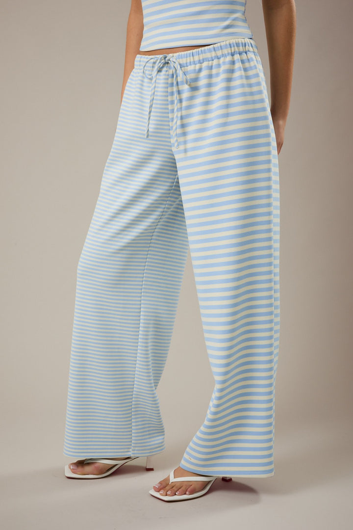 Person wearing light blue and white striped pants on a beige background