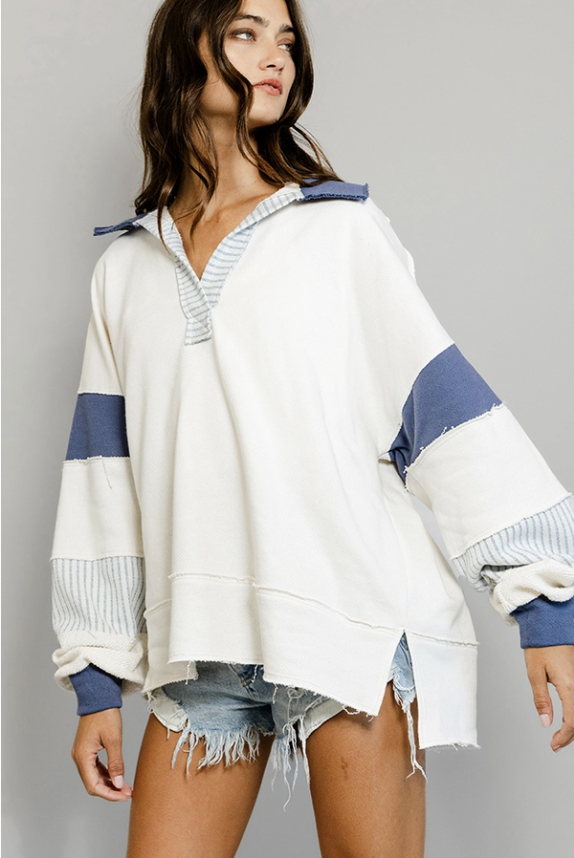 Woman wearing a white and blue striped sweater with denim shorts on a gray background