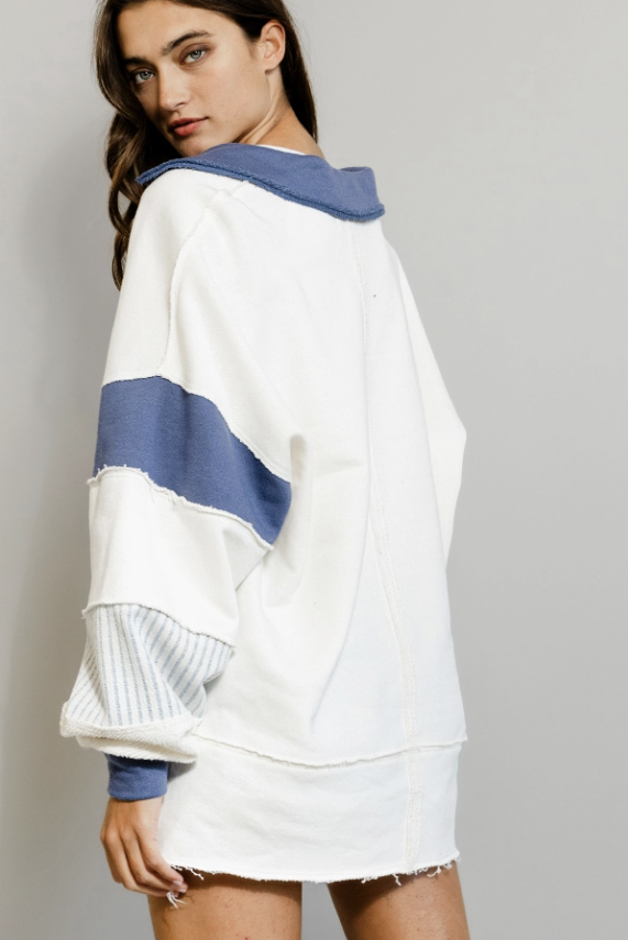 White sweatshirt with blue accents worn by a model on a gray background