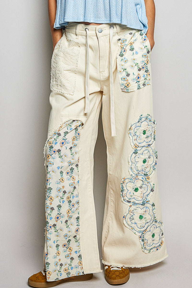 Floral embroidered pants worn by a person on a plain background