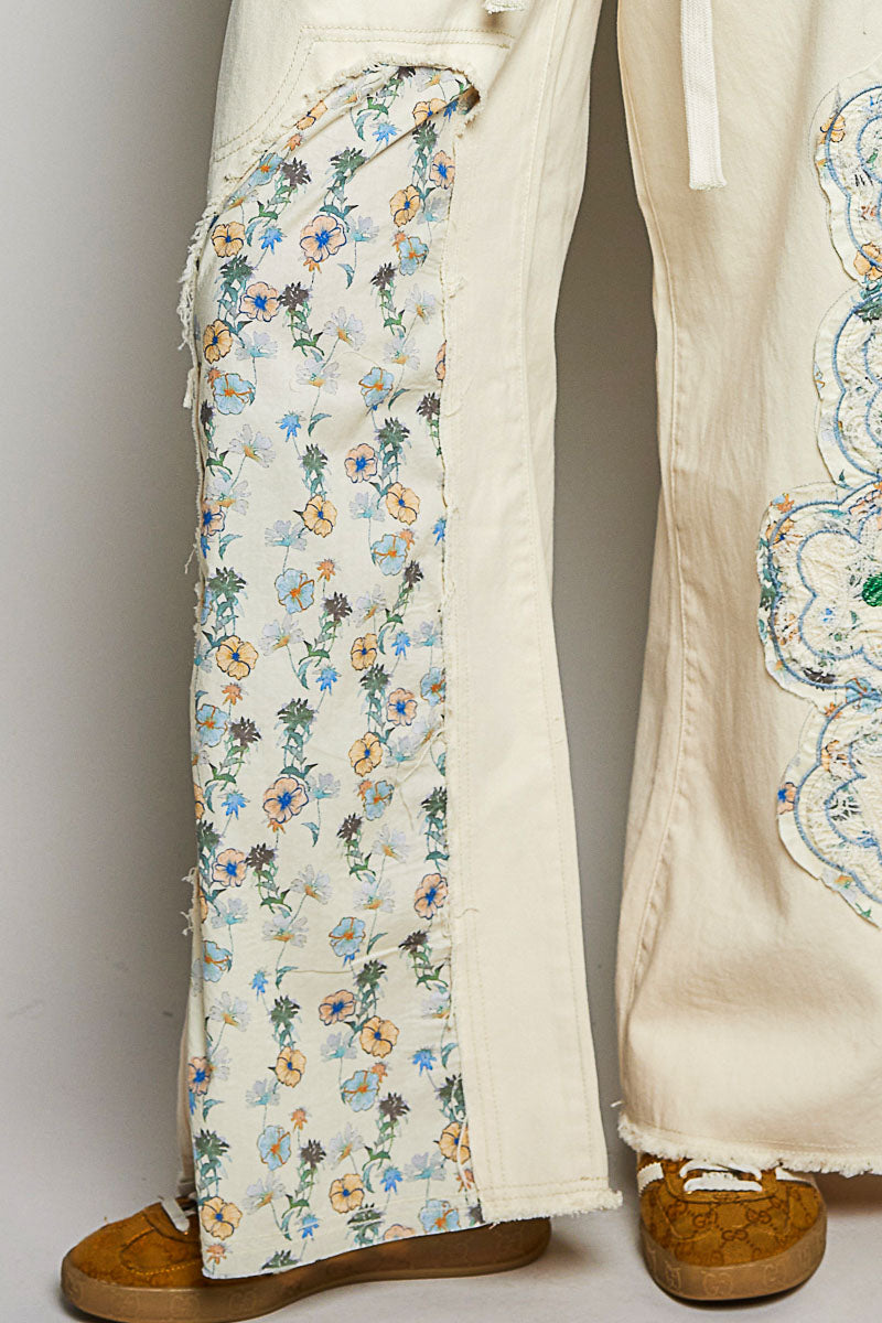 Beige pants with floral embroidery on a plain background