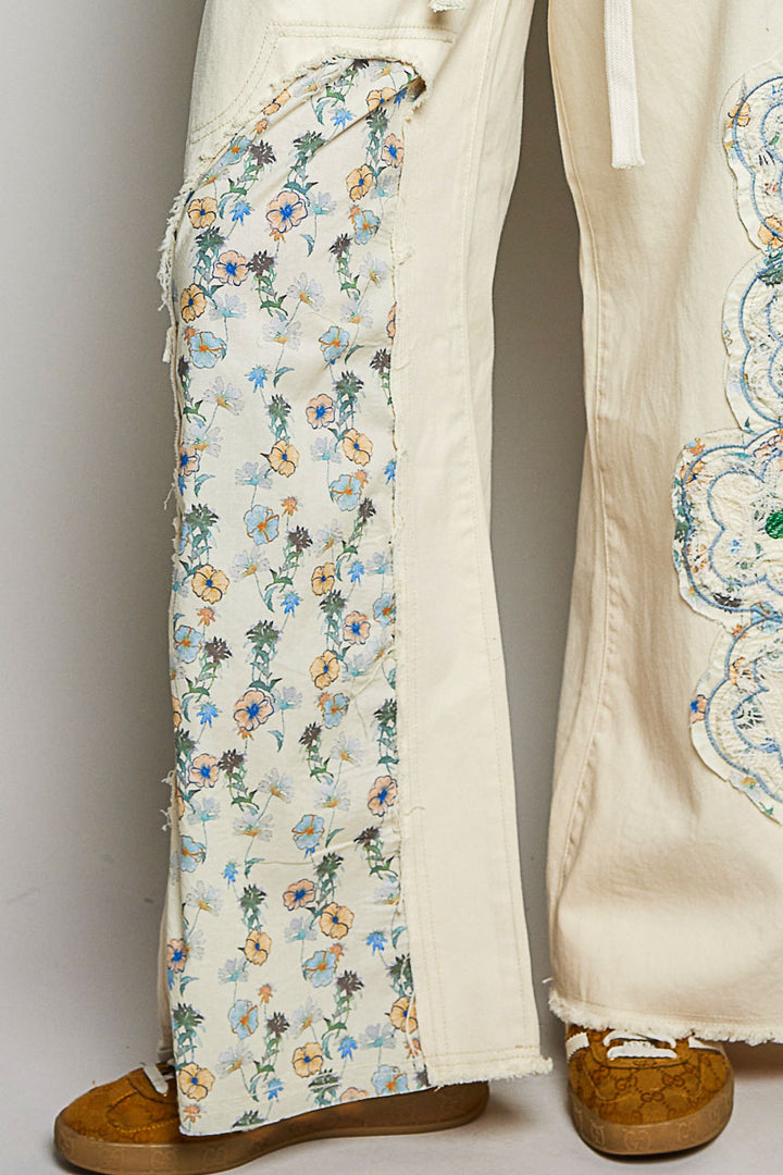 Beige pants with floral embroidery on a plain background