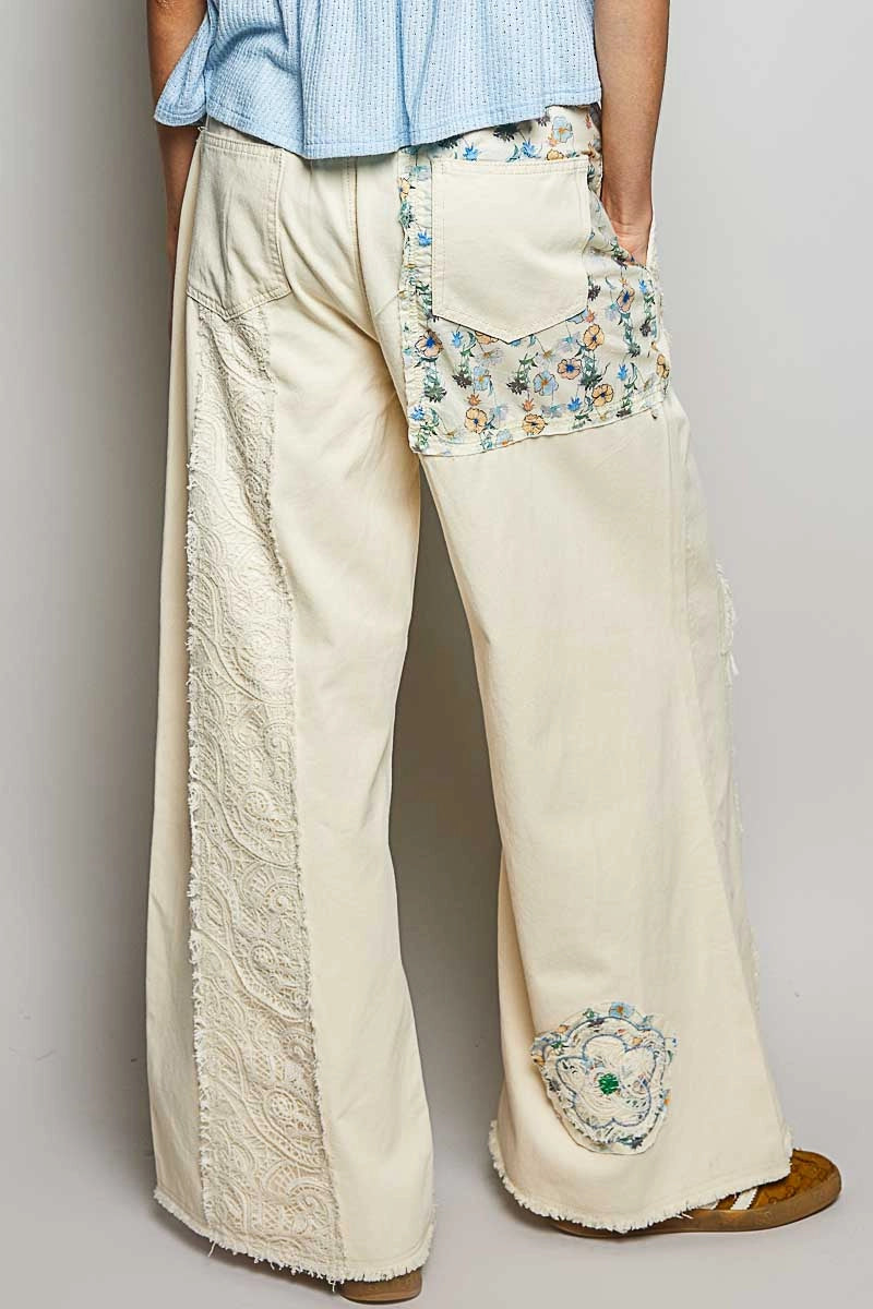 Beige wide-leg pants with floral embroidery on a plain background