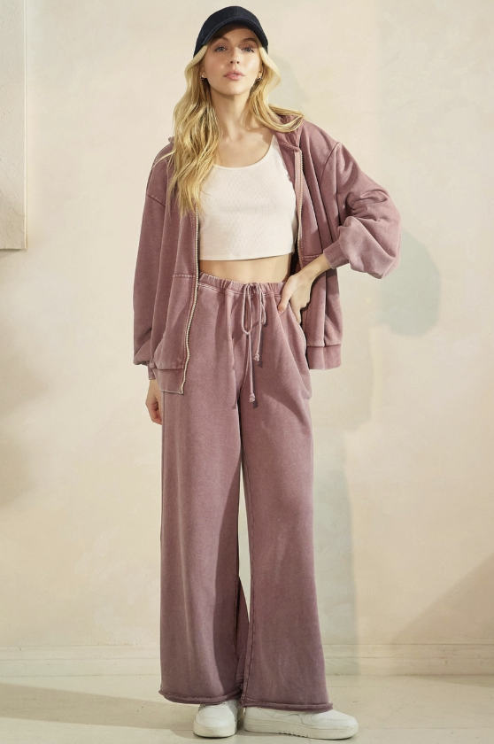 Woman wearing a pink tracksuit and white sneakers in a minimalistic setting