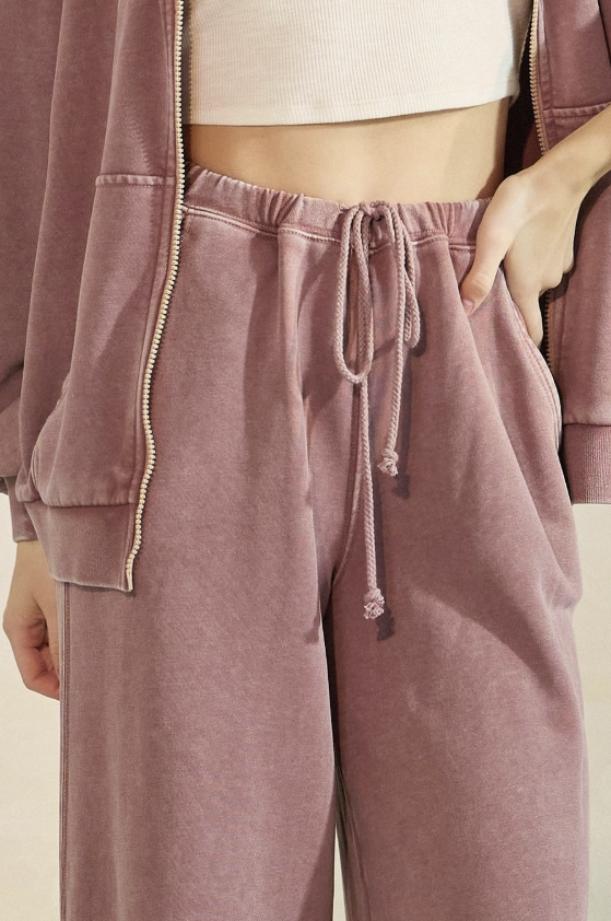 Person wearing a mauve tracksuit with a neutral background