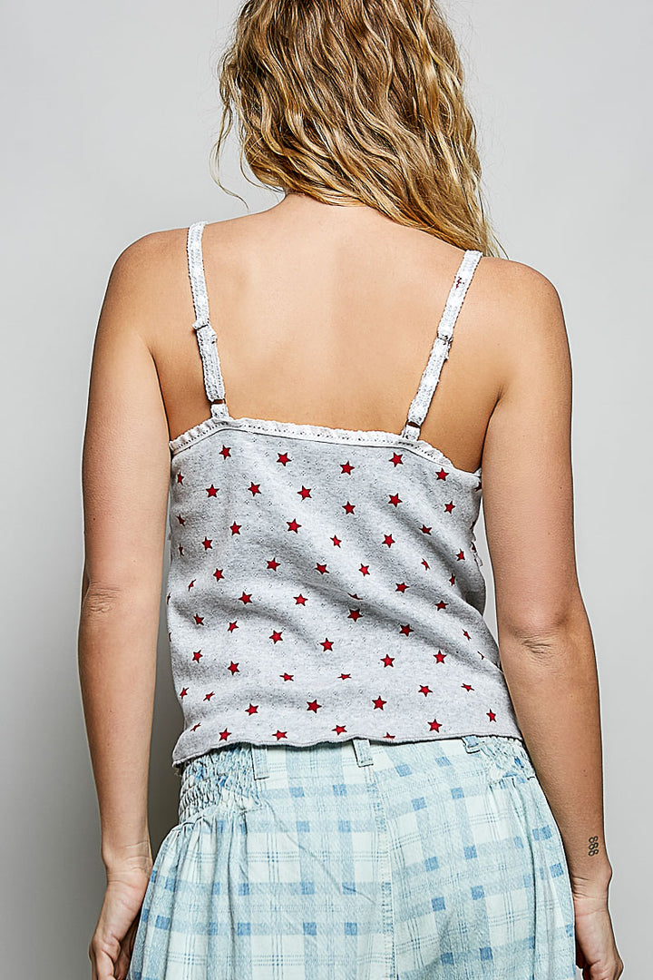 Person wearing a gray tank top with red star pattern and light blue plaid shorts on a plain background