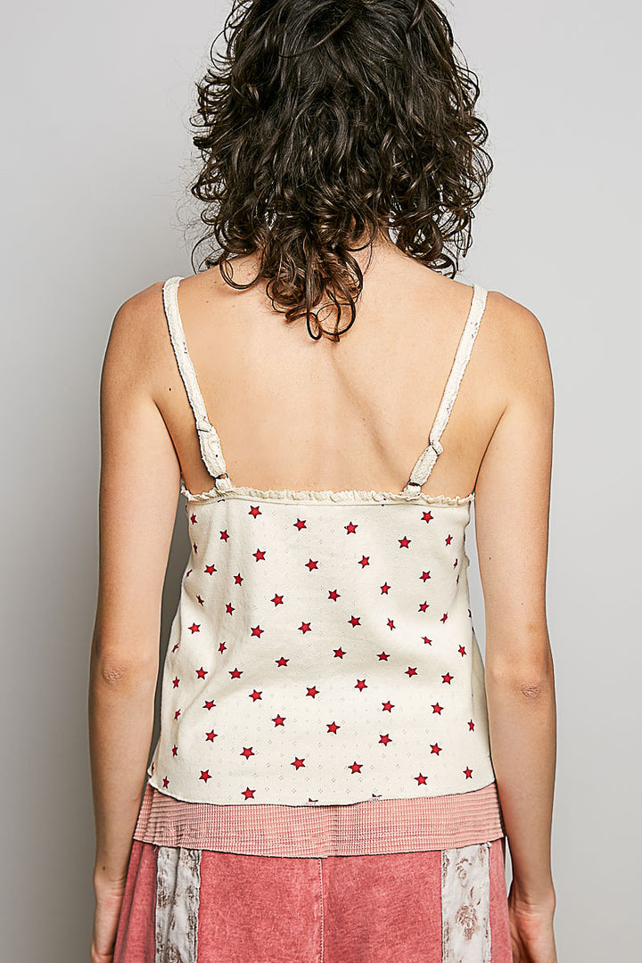 Woman wearing a white tank top with red star patterns on a plain background