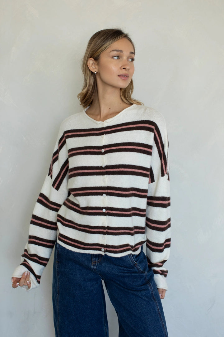 Woman wearing a striped sweater and blue jeans against a plain background