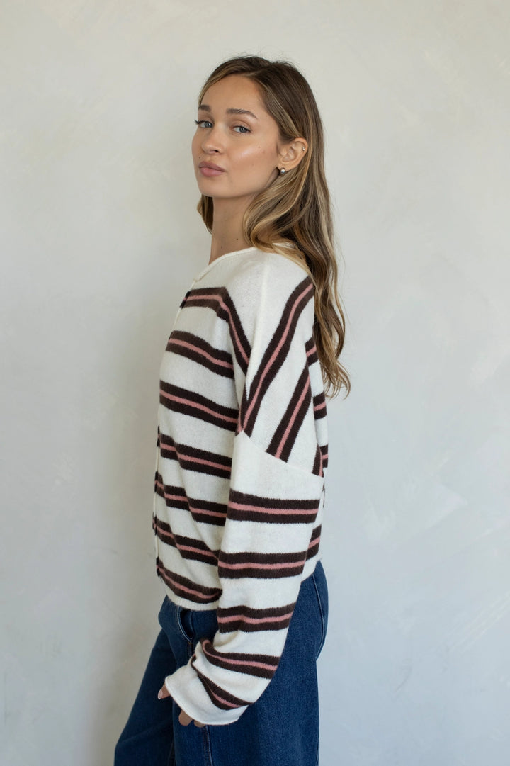 Woman wearing a white sweater with red and black horizontal stripes against a plain background