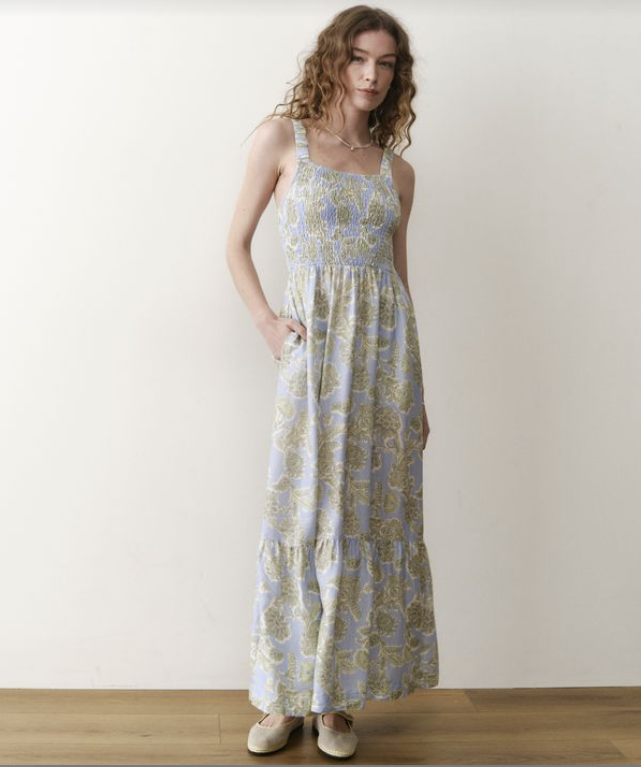 Woman wearing a floral patterned dress against a white wall.
