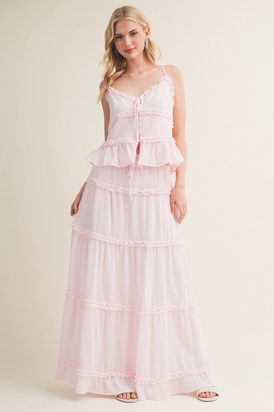 Woman wearing a pink tiered dress against a plain background