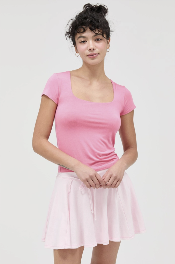 Woman wearing pink tee in front of plain background