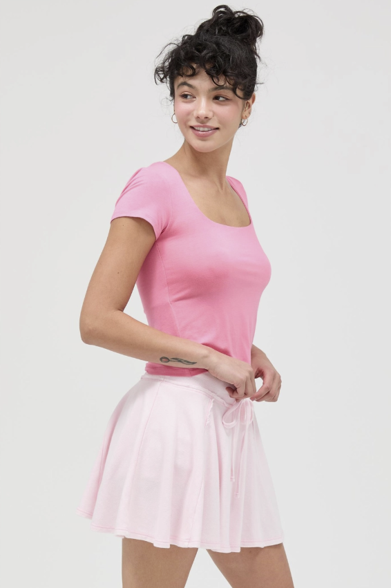Woman wearing a pink top and skirt on a white background
