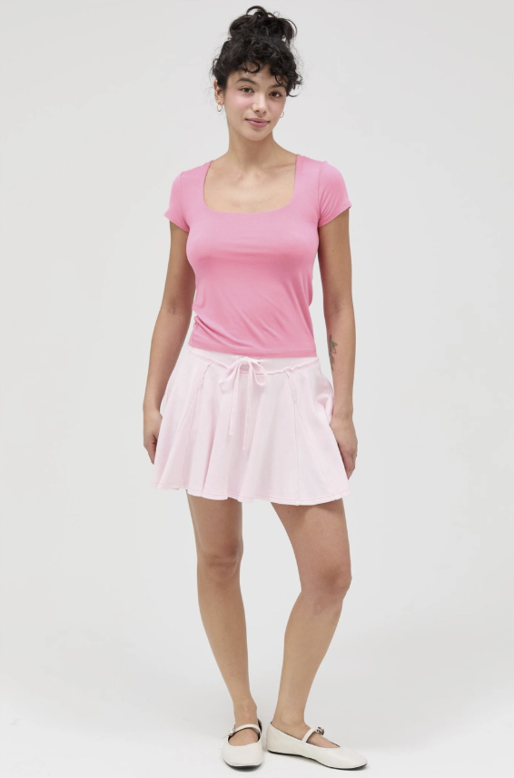 Woman wearing a pink top and skirt on a white background