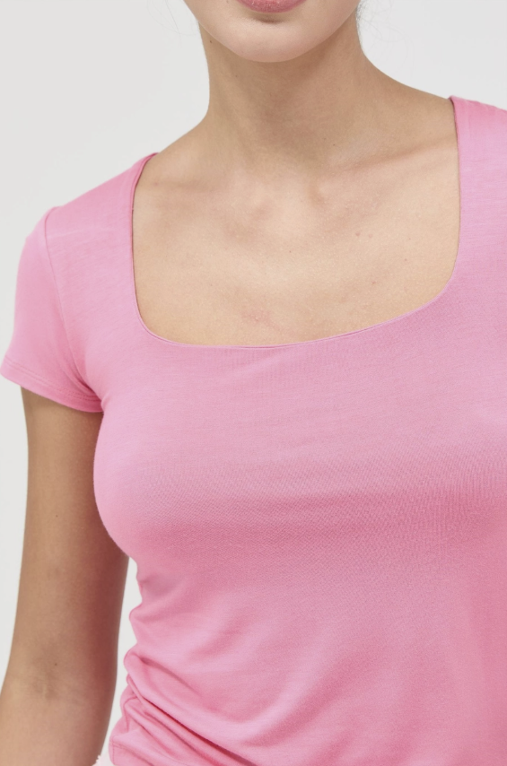 Close-up of a person wearing a pink top with a plain background