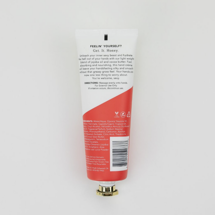 The back of a hand cream tube, showing the text and barcode, with a red and white design and a gold cap, photographed on a light gray background.