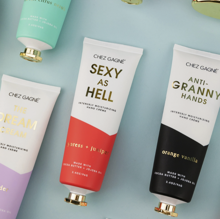Four tubes of Chez Gagné hand cream arranged diagonally on a light blue background. The tubes are white with different accent colors: mint green, coral red, and black, with gold caps and gold/black lettering.