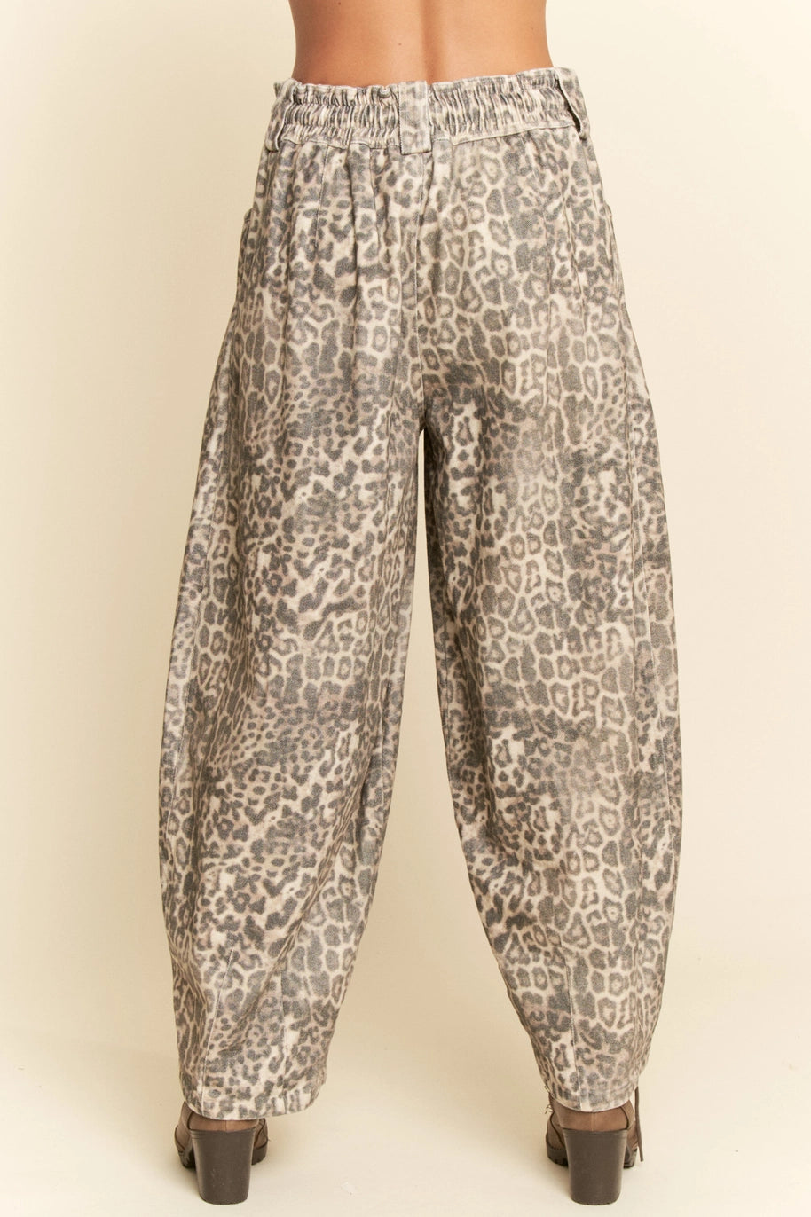 Leopard print pants worn by a person on a beige background