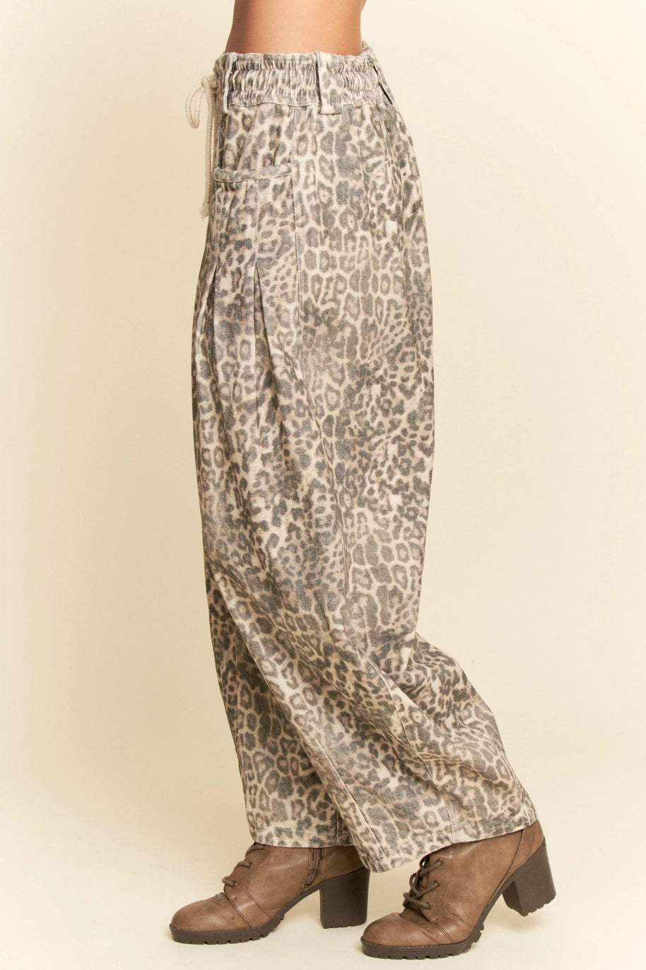 Leopard print pants worn by a person on a beige background