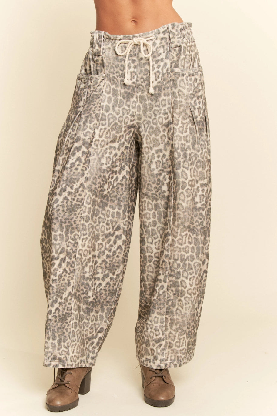 Leopard print pants worn by a person on a beige background