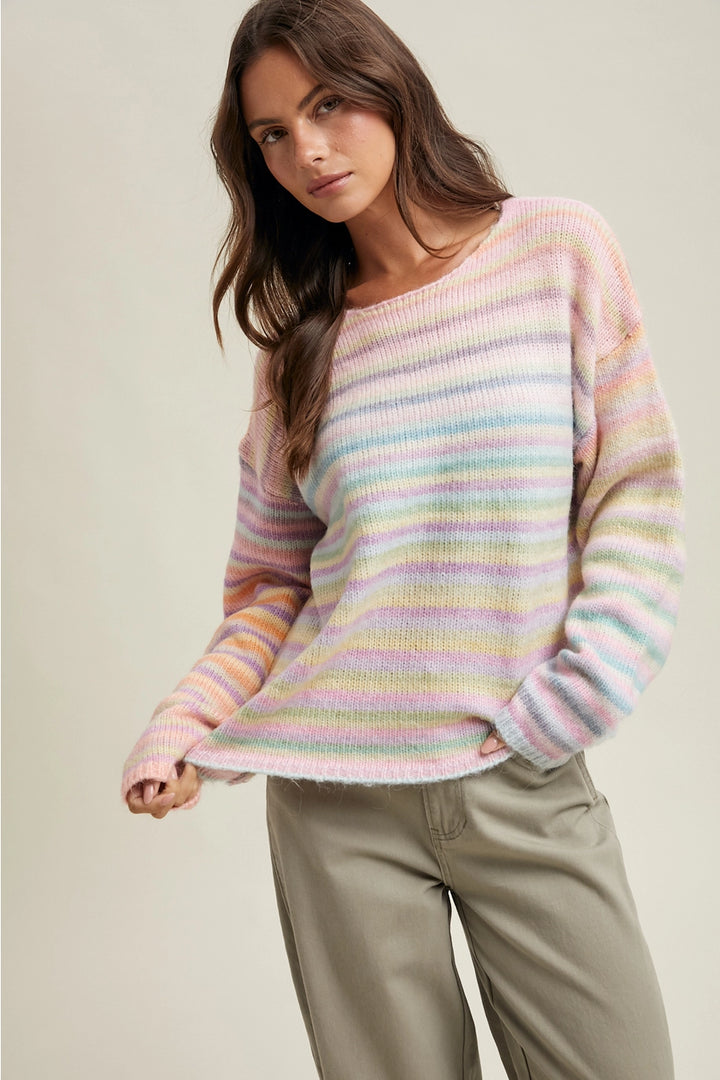 Woman wearing pastel striped sweater with olive pants on plain background