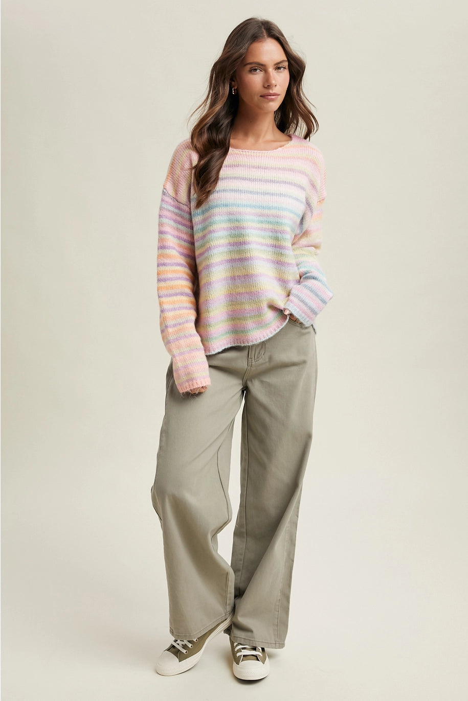 Woman wearing pastel striped sweater and olive pants on plain background