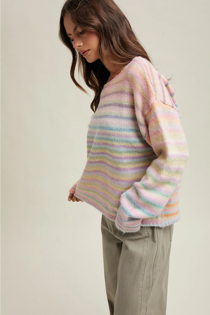 Woman wearing pastel striped sweater and olive pants on plain background