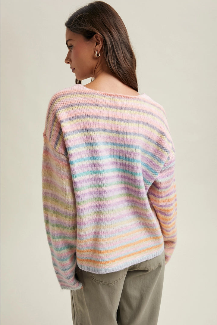 Woman wearing pastel striped sweater and olive pants on plain background
