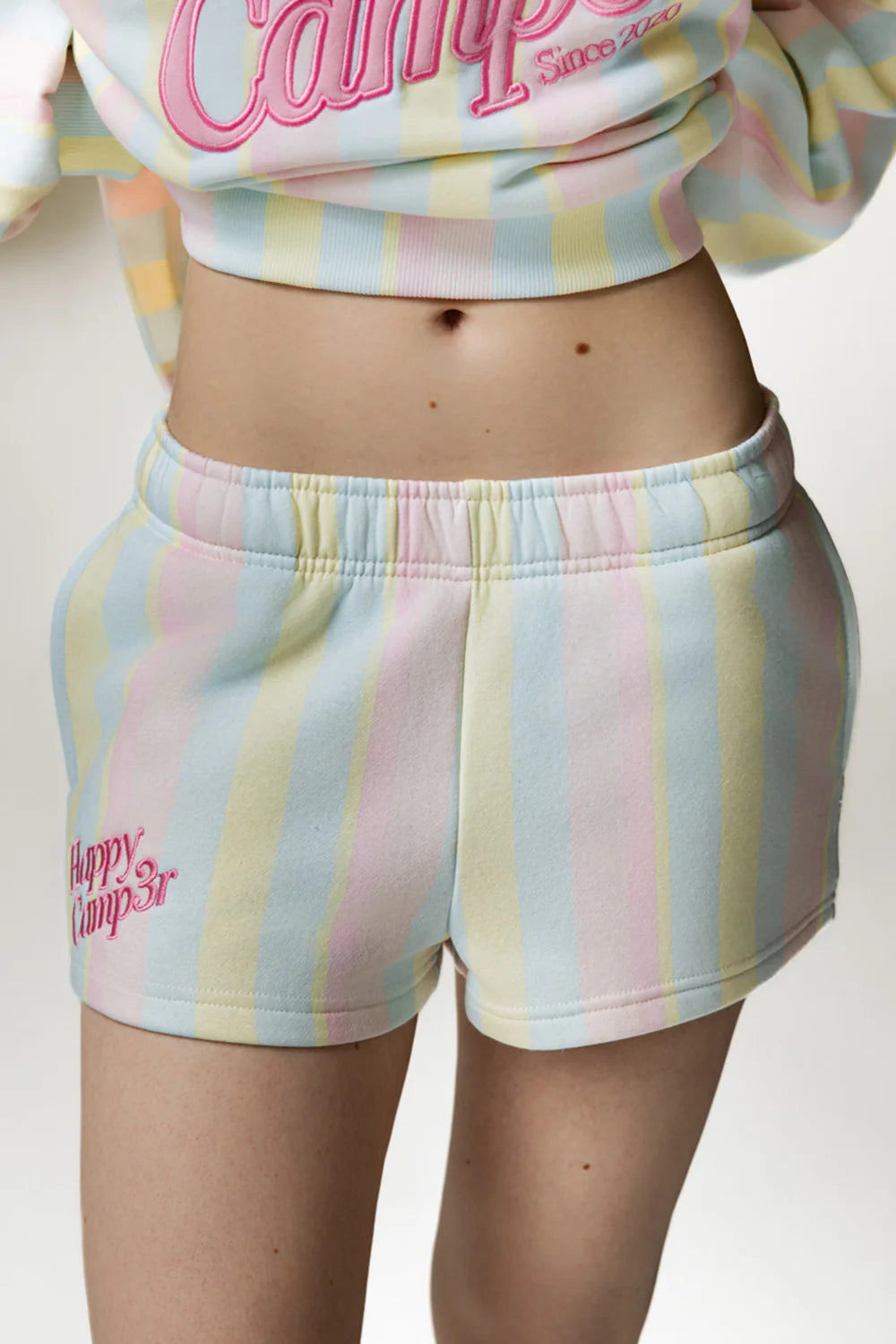 Person wearing pastel stripe shorts on white background