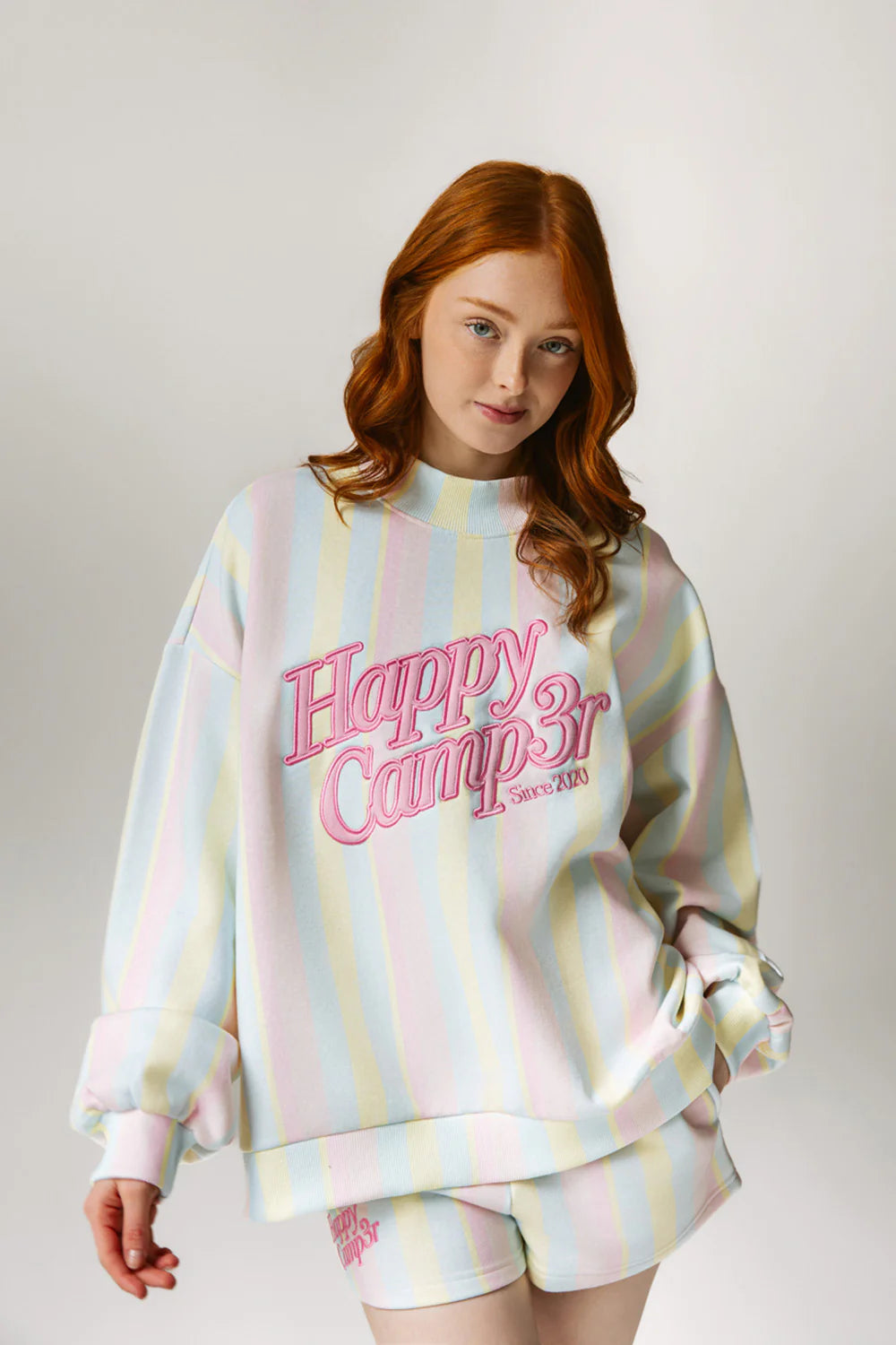 Person wearing a pastel striped sweatshirt with &