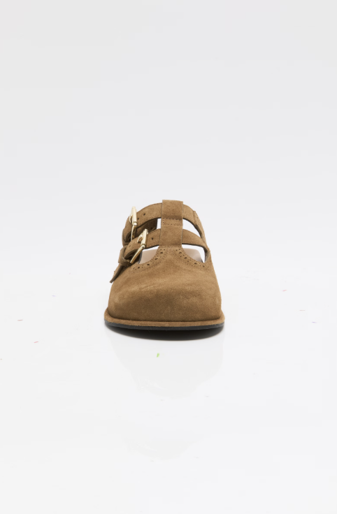 A single tan suede T-strap sandal with gold-tone buckle details, photographed from the front on a clean white background.