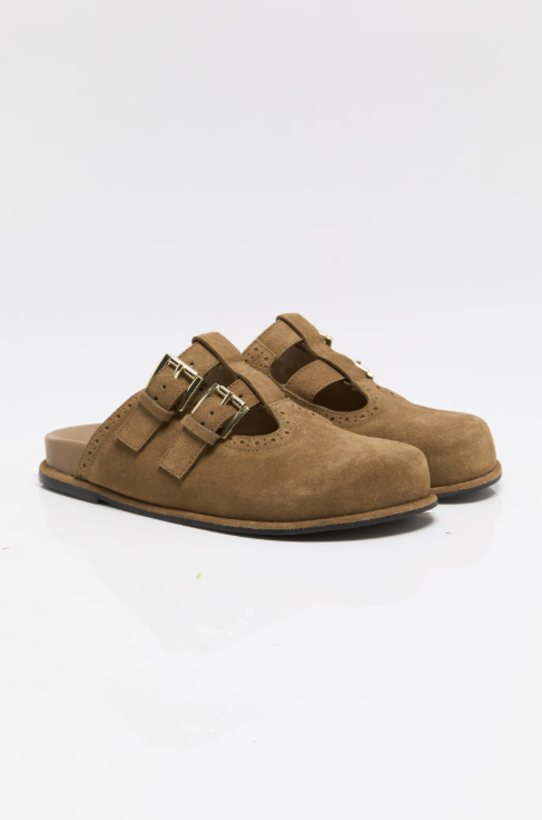 Pair of tan suede mules with buckle detail on white background