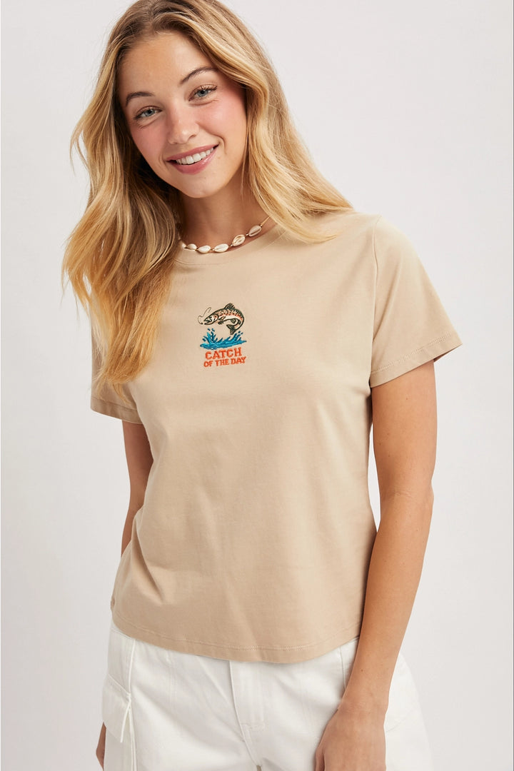 Woman wearing a beige t-shirt with a graphic design on a white background