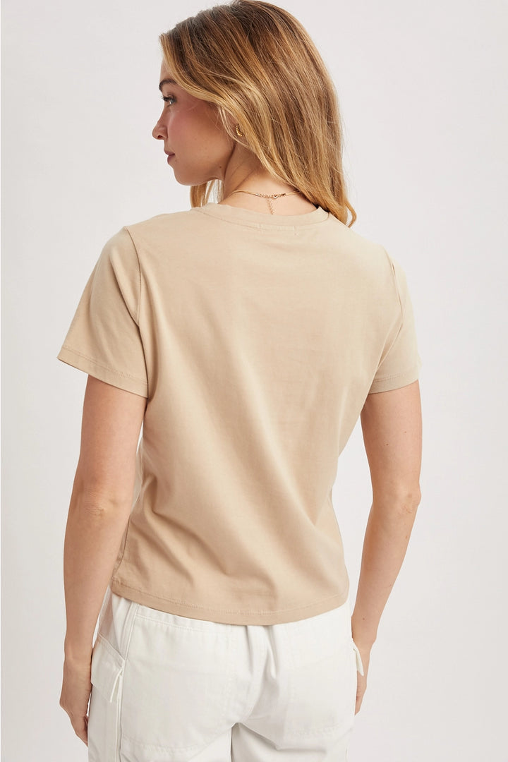 Woman wearing a beige t-shirt and white pants on a plain background